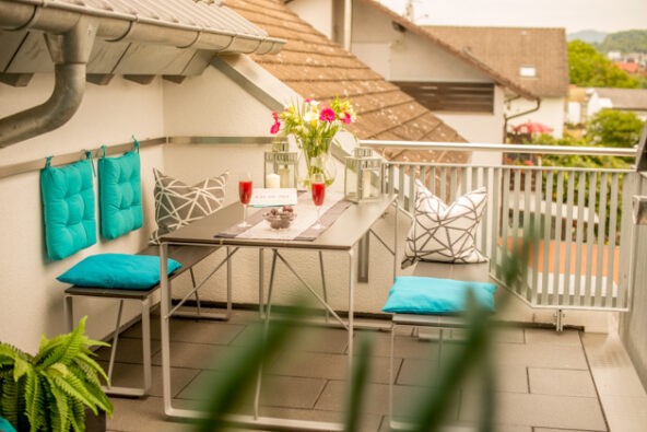 Schöner Dachbalkon mit Tisch, Bänken, Wipp-Sessel und Blick in den Garten